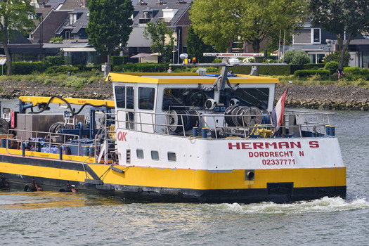 Dordrecht South Holland Netherlands 31 May 2026 View of the fuel service ship Herman S navigating the Oude Maas river with residential buildings in the background.
