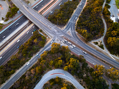 Aerial view of Mitchell Freeway with cars driving on multi lane roads surrounded by lush trees during golden hour in Perth Western Australia Australia. Aerial view of Mitchell Freeway with cars driving on multi lane roads surrounded by lush trees during golden hour in Perth Western Australia Australia.