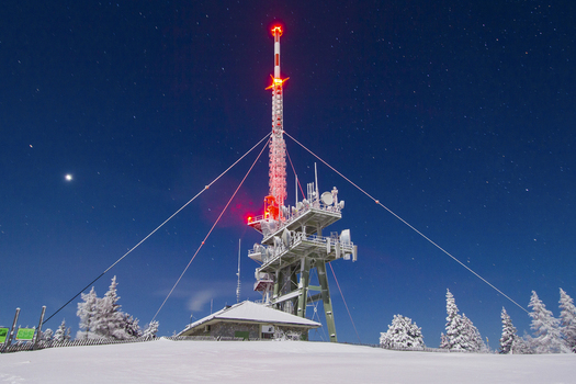 View of a communications tower with bright red lights piercing the cold clear night sky above a snow covered landscape Schöckl Styria Austria. View of a communications tower with bright red lights piercing the cold clear night sky above a snow covered landscape Schöckl Styria Austria.