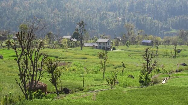 View of a rural village nestled among green fields and hills Nepal.