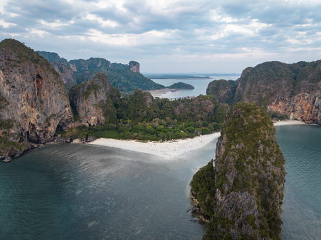 Aerial view of towering limestone cliffs embrace the turquoise sea framing the pristine sands of Railay Beach Krabi Thailand. Aerial view of towering limestone cliffs embrace the turquoise sea framing the pristine sands of Railay Beach Krabi Thailand.