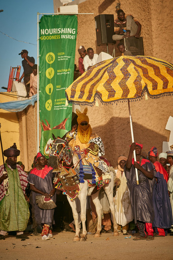Zaria Nigeria 22 March 2026 View of a regal rider on a richly adorned white horse parading through sun kissed streets surrounded by a vibrant festive crowd. Zaria Nigeria 22 March 2026 View of a regal rider on a richly adorned white horse parading through sun kissed streets surrounded by a vibrant festive crowd.