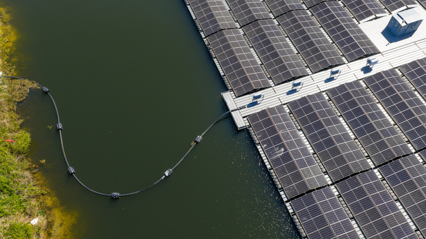 Aerial view of a floating solar farm with rows of photovoltaic panels on a lake and a connecting cable to the shore in Zwolle Overijssel Netherlands. Aerial view of a floating solar farm with rows of photovoltaic panels on a lake and a connecting cable to the shore in Zwolle Overijssel Netherlands.