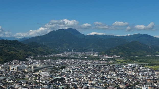Aerial view of the cityscape of Aoi and Suruga Wards in Shizuoka City featuring dense residential areas and lush green mountains under a clear blue sky in Shizuoka Shizuoka Japan.