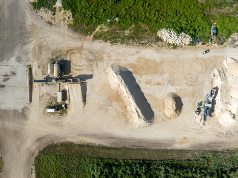 Aerial view of the restoration of North Field Base showing industrial equipment large sand piles and dirt roads in Northern Tinian Tinian Northern Mariana Islands.