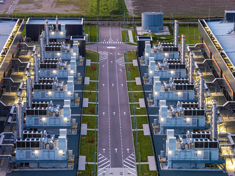 Aerial view of Microsoft Data Center with rows of industrial cooling units central access road and surrounding green lawns in Middenmeer North Holland Netherlands.