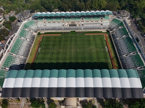 Aerial view of Maguwoharjo Stadium featuring a green football pitch tiered seating with green and white patterns and a large roof structure in Kecamatan Depok Daerah Istimewa Yogya Indonesia.