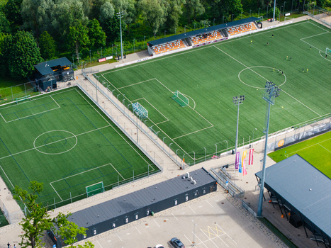 Riga Latvia 05 July 2026 Aerial view of LNK Sporta Parks featuring multiple artificial turf soccer fields stadium seating and floodlight towers. Riga Latvia 05 July 2026 Aerial view of LNK Sporta Parks featuring multiple artificial turf soccer fields stadium seating and floodlight towers.