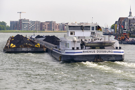 Dordrecht South Holland 31 May 2026 View of the Rhenus Duisburg cargo barge transporting coal along the Oude Maas river with urban buildings in the background.