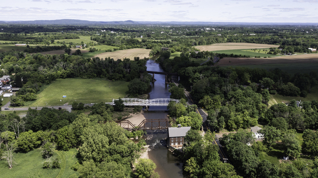 Aerial view of the historic Neshanic Station area featuring the river multiple bridges and surrounding lush green fields and trees in Branchburg New Jersey United States.