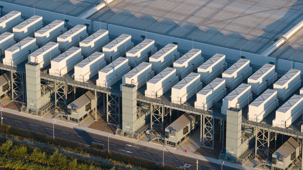Aerial view of a large industrial facility featuring rows of white cooling units on a steel structure with a road and vegetation below in Eemshaven Groningen Netherlands.