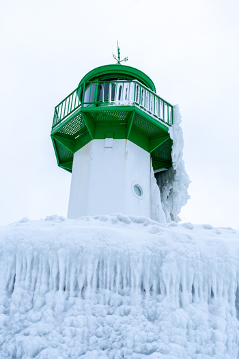 View of the Molenfeuer Sassnitz lighthouse covered in thick ice and snow during a cold winter day in Sassnitz Mecklenburg Vorpommern Germany.