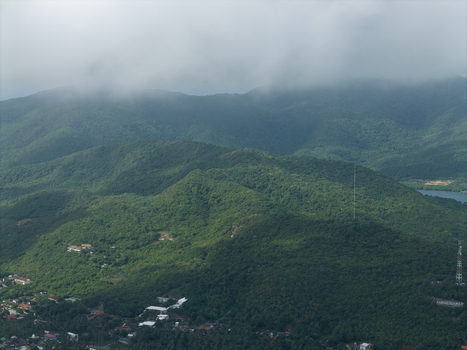 Aerial view of dense verdant hills rolling towards the horizon under a blanket of soft low hanging clouds Karimunjawa Central Java Indonesia. Aerial view of dense verdant hills rolling towards the horizon under a blanket of soft low hanging clouds Karimunjawa Central Java Indonesia.
