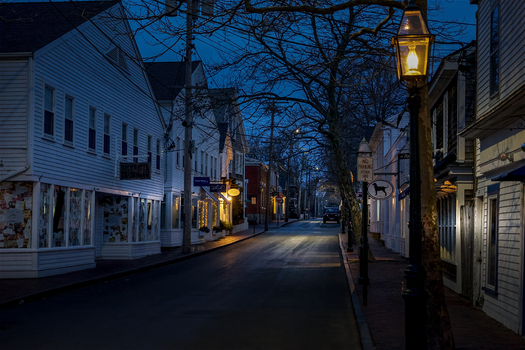 View of Martha s Vineyard featuring historic white wooden buildings and glowing street lamps along a quiet street at twilight in Edgartown Massachusetts United States.