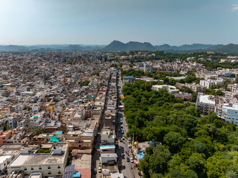 Aerial view of the cityscape of Udaipur with dense urban housing a bustling road and lush green trees in Udaipur Rajasthan India.