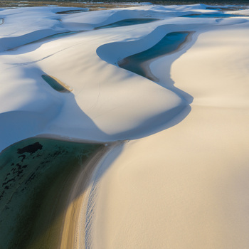 Aerial view of the white sand dunes and turquoise lagoons of Parque Nacional dos Lencois Maranhenses under soft golden light Lencois Maranhenses MA Brazil. Aerial view of the white sand dunes and turquoise lagoons of Parque Nacional dos Lencois Maranhenses under soft golden light Lencois Maranhenses MA Brazil.