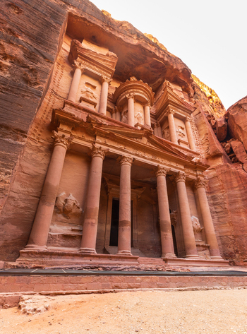 View of the Treasury carved into the rose red sandstone cliffs of Petra featuring intricate columns and classical architecture in Wadi Musa Ma an Governorate Jordan. View of the Treasury carved into the rose red sandstone cliffs of Petra featuring intricate columns and classical architecture in Wadi Musa Ma an Governorate Jordan.
