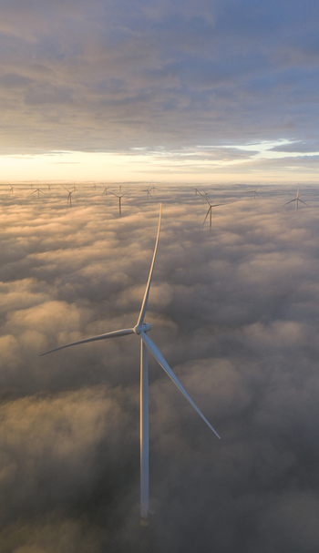 Aerial view of Windpark Fryslan wind turbines rising above a thick layer of clouds during a golden sunset in Breezanddijk Friesland Netherlands.