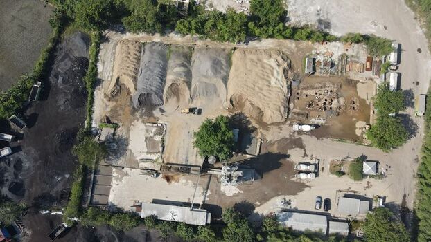 Aerial view of an industrial construction site featuring large piles of sand and gravel concrete mixers and trucks parked on a dirt lot in Cilegon Banten Indonesia. Aerial view of an industrial construction site featuring large piles of sand and gravel concrete mixers and trucks parked on a dirt lot in Cilegon Banten Indonesia.