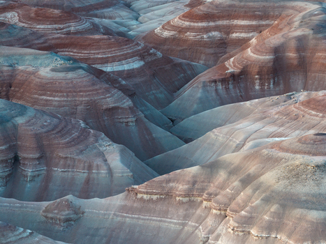 Aerial view of layered earth tones create a painterly landscape where shadows accentuate the undulating terrain. Hanksville Utah United States. Aerial view of layered earth tones create a painterly landscape where shadows accentuate the undulating terrain. Hanksville Utah United States.