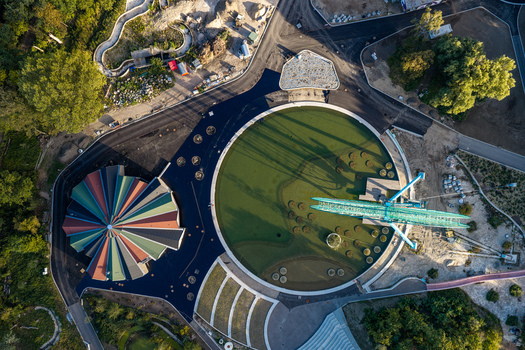 Aerial view of Spreepark in Berlin featuring a colorful carousel roof a large circular plaza and a Ferris wheel structure surrounded by lush greenery in Berlin Berlin Germany. Aerial view of Spreepark in Berlin featuring a colorful carousel roof a large circular plaza and a Ferris wheel structure surrounded by lush greenery in Berlin Berlin Germany.
