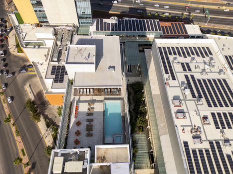 Aerial view of solar panels installed on the rooftops of a modern building complex featuring a swimming pool and lounge area in Chihuahua Chihuahua Mexico. Aerial view of solar panels installed on the rooftops of a modern building complex featuring a swimming pool and lounge area in Chihuahua Chihuahua Mexico.