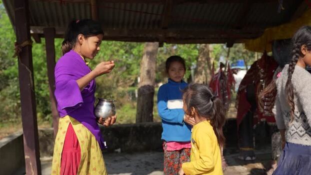 View of a girl holding a metal pot under a shelter Nepal.