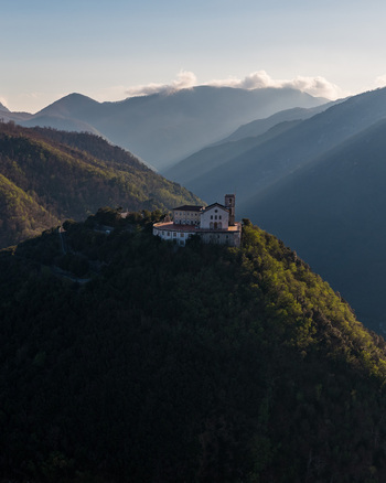 Aerial view of Santuario del Santissimo Salvatore perched on a lush hilltop surrounded by the Picentini Mountains under soft evening light in Montella Campania Italy. Aerial view of Santuario del Santissimo Salvatore perched on a lush hilltop surrounded by the Picentini Mountains under soft evening light in Montella Campania Italy.