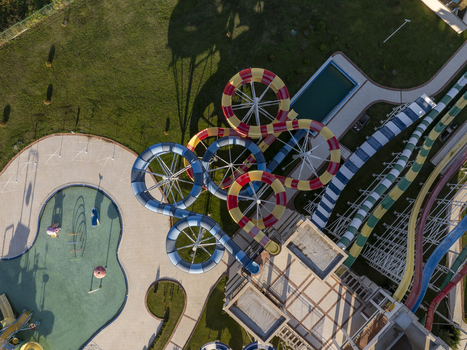 Aerial view of a colorful water park featuring winding slides and a swimming pool surrounded by green lawns in Bulgaria. Aerial view of a colorful water park featuring winding slides and a swimming pool surrounded by green lawns in Bulgaria.