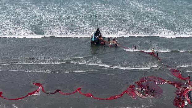Aerial view of fishermen pulling a red net near a boat in Bangladesh. Aerial view of fishermen pulling a red net near a boat in Bangladesh.