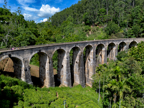 Aerial view of the historic Nine Arch Bridge surrounded by lush green tea plantations and dense forest in Demodara Uva Province Sri Lanka. Aerial view of the historic Nine Arch Bridge surrounded by lush green tea plantations and dense forest in Demodara Uva Province Sri Lanka.