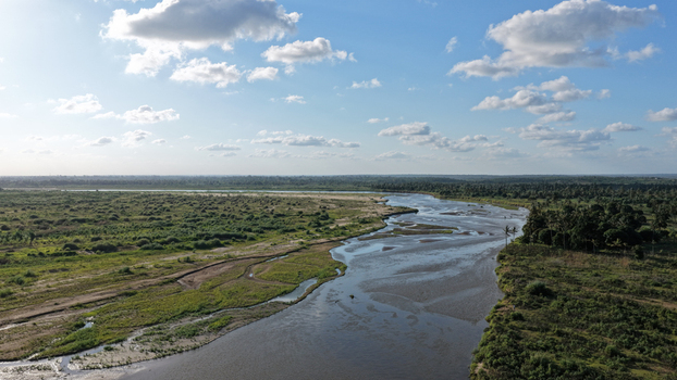 Aerial view of River Sabaki flowing through the lush green landscape of the coastal region under a bright blue sky with scattered clouds in Malindi Kilifi County Kenya.