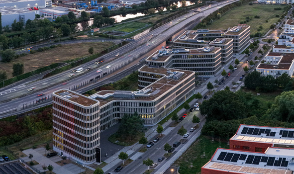 Aerial view of the Brain Box Campus in Adlershof featuring modern office buildings with green roofs adjacent to a highway with traffic in Berlin Berlin Germany. Aerial view of the Brain Box Campus in Adlershof featuring modern office buildings with green roofs adjacent to a highway with traffic in Berlin Berlin Germany.