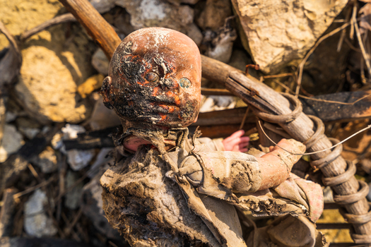 View of a damaged and dirty doll lying amidst debris rocks and wooden sticks near the shore of Lake Varna Varna Bulgaria. View of a damaged and dirty doll lying amidst debris rocks and wooden sticks near the shore of Lake Varna Varna Bulgaria.