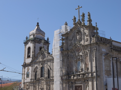 View of the ornate baroque facade and bell tower of the Igreja dos Congregados with scaffolding on the side under a clear blue sky in Porto Porto District Portugal. View of the ornate baroque facade and bell tower of the Igreja dos Congregados with scaffolding on the side under a clear blue sky in Porto Porto District Portugal.