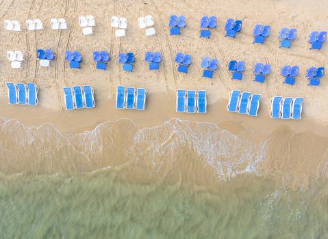 Aerial view of rows of blue and white sunbeds on the sand near the gentle waves of the Mediterranean Sea at Bat Yam beach in Bat Yam Center District Israel. Aerial view of rows of blue and white sunbeds on the sand near the gentle waves of the Mediterranean Sea at Bat Yam beach in Bat Yam Center District Israel.
