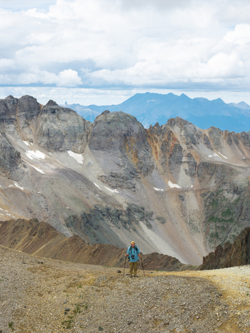 Aerial view of a hiker standing on the rocky Yankee Boy Basin Trail with the rugged peaks of Mount Sneffels and the San Juan Mountain Range in the background Ouray Colorado United States. Aerial view of a hiker standing on the rocky Yankee Boy Basin Trail with the rugged peaks of Mount Sneffels and the San Juan Mountain Range in the background Ouray Colorado United States.