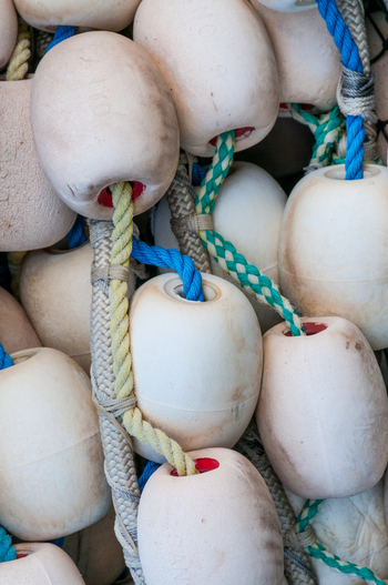 View of fishing net floats with colorful ropes and weathered plastic buoys in Canada. View of fishing net floats with colorful ropes and weathered plastic buoys in Canada.