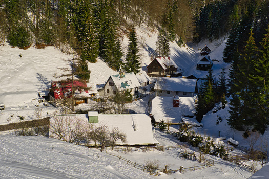 View of snow dusted cottages nestled amongst the evergreen trees a winter scene of tranquil beauty and colorful roofs Moce Banska Bystrica Region Slovakia.