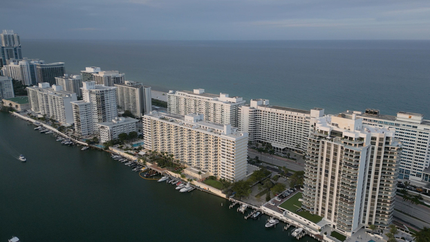 Aerial view of the Miami Beach skyline featuring high rise residential buildings along the waterfront with boats docked in the canal and Atlantic Ocean Miami Beach Florida United States. Aerial view of the Miami Beach skyline featuring high rise residential buildings along the waterfront with boats docked in the canal and Atlantic Ocean Miami Beach Florida United States.