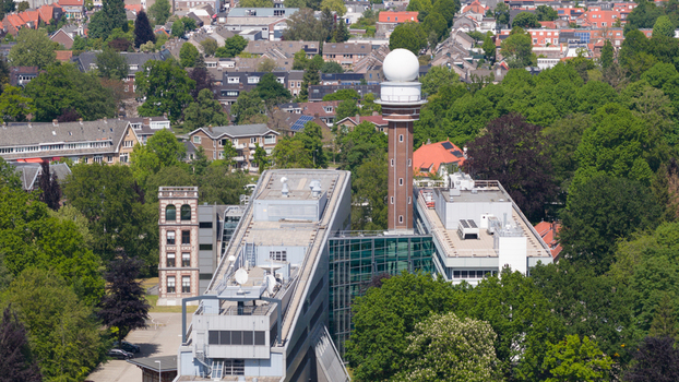 Aerial view of the KNMI headquarters featuring the iconic radar tower and modern office buildings surrounded by lush green trees in De Bilt Utrecht Netherlands. Aerial view of the KNMI headquarters featuring the iconic radar tower and modern office buildings surrounded by lush green trees in De Bilt Utrecht Netherlands.
