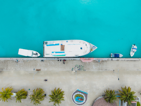 Aerial view of boats docked along a concrete pier contrasting against the turquoise water Vashafaru Island Thiladhummathi Atoll Maldives. Aerial view of boats docked along a concrete pier contrasting against the turquoise water Vashafaru Island Thiladhummathi Atoll Maldives.