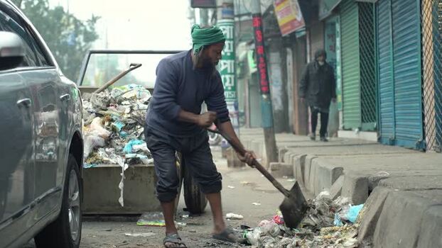 View of a man shoveling garbage on a street in Bogura Bangladesh. View of a man shoveling garbage on a street in Bogura Bangladesh.