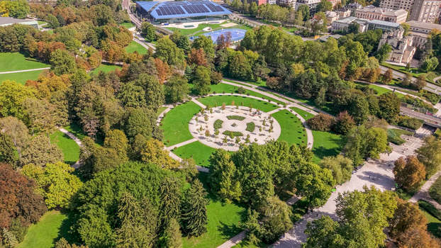 Aerial view of Tivoli Park featuring a circular central plaza surrounded by lush green trees walking paths and manicured lawns in Ljubljana Slovenia.