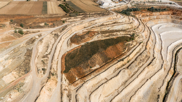 Aerial view of the Besenovo open pit mine featuring terraced excavation levels dirt access roads and surrounding agricultural fields in Besenovo Vojvodina Serbia. Aerial view of the Besenovo open pit mine featuring terraced excavation levels dirt access roads and surrounding agricultural fields in Besenovo Vojvodina Serbia.