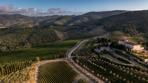 Aerial view of a historic stone villa surrounded by rows of vineyards olive groves and a cypress lined road on the rolling hills of Greve in Chianti Tuscany Italy. Aerial view of a historic stone villa surrounded by rows of vineyards olive groves and a cypress lined road on the rolling hills of Greve in Chianti Tuscany Italy.