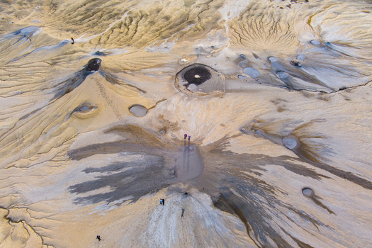Aerial view of the Mud Volcanoes of Paclele Mari showcasing unique geological formations grey mud craters and a barren landscape with people for scale in Paclele Buzau County Romania.