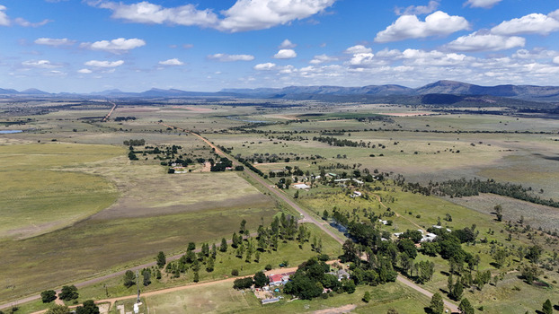 Aerial view of the rural settlement of Alma featuring a long straight road through green fields and distant mountains in Waterberg District Municipality Limpopo South Africa. Aerial view of the rural settlement of Alma featuring a long straight road through green fields and distant mountains in Waterberg District Municipality Limpopo South Africa.