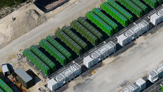 Aerial view of a battery energy storage system facility featuring rows of green battery containers and white power conversion units on a gravel site in Saleux Hauts de France France.
