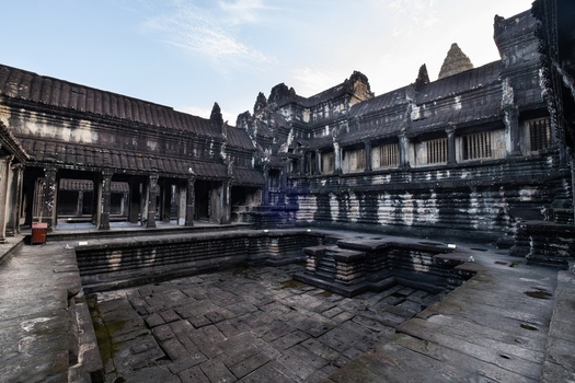 View of the ancient stone courtyard and reflecting pool within the Angkor Wat temple complex featuring weathered sandstone walls in Krong Siem Reap Siem Reap Province Cambodia.